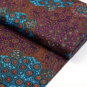 May include: A brown, purple, blue and orange fabric with a repeating pattern of circles and dots. The fabric is folded in half and the pattern is visible on both sides.