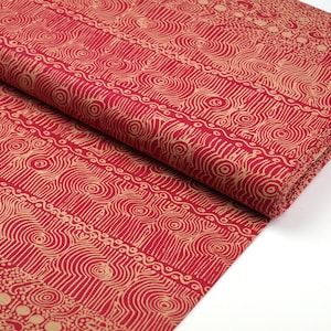 May include: Red fabric with a beige pattern of circles, lines, and dots. The fabric is folded in half.