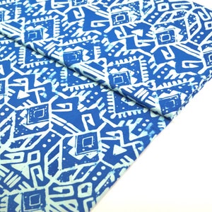 Könnte beinhalten: Blauer und weißer Stoff mit geometrischem Muster. Der Stoff ist in der Mitte gefaltet und das Muster ist auf beiden Seiten sichtbar.