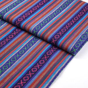 Op de afbeelding: Gestroomde stof met een kleurrijk geometrisch patroon in tinten blauw, rood, groen en wit. De stof heeft een geweven textuur en is perfect voor knutselprojecten.