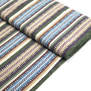 Op de afbeelding: Gestroomde stof met een groen, blauw, rood en beige patroon. De stof heeft een geweven textuur en is dubbelgevouwen.