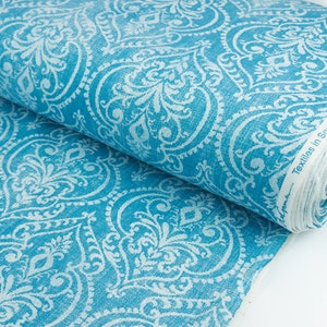 Op de afbeelding: Een rol tealblauwe stof met een wit damastpatroon. De stof is gemaakt in Zuid-Afrika.