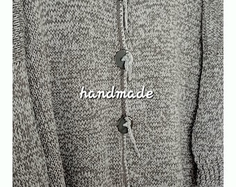May include: A grey and white knitted cardigan with three large buttons and a V-neck. The word "handmade" is written across the front. The brand name "ADeKii" is visible at the top.