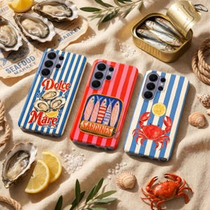 Può includere: Tre custodie per telefoni colorate con disegni a tema frutti di mare. Una custodia ha strisce blu e bianche con le parole "Dolce Mare" e illustrazioni di ostriche. Un'altra ha strisce rosse e rosa con un'illustrazione di sardine. La terza ha strisce blu e bianche con un'illustrazione di granchio e limone.
