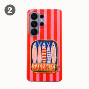 May include: A phone case with a red and pink striped background. The case features a rectangular graphic of a sardine can with five colorful fish. The word "SARDINES" is printed on the can.