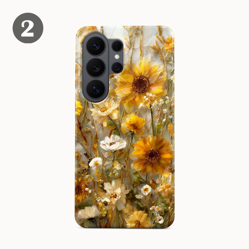 May include: A phone case featuring a floral design with sunflowers and other yellow and white flowers. The case has a glossy finish and a camera cutout. The design is a mix of yellow, white, and brown tones.