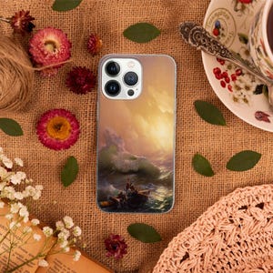 Peut inclure: Une coque de t&eacute;l&eacute;phone avec une peinture d'une mer orageuse avec un bateau et des personnes &agrave; l'int&eacute;rieur. Le ciel est d'un orange et d'un jaune vif. La coque de t&eacute;l&eacute;phone est blanche et a une d&eacute;coupe pour l'objectif de l'appareil photo.