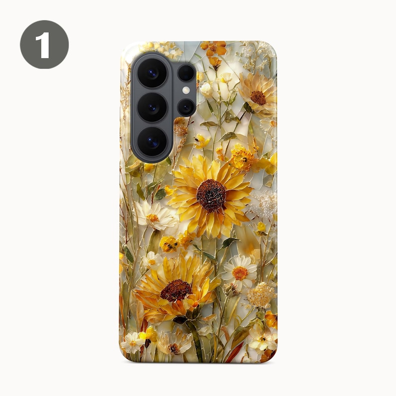 May include: A phone case featuring a vibrant floral design. The case showcases a field of sunflowers and other wildflowers in shades of yellow, white, and brown. The design has a textured, artistic appearance, with a light background.