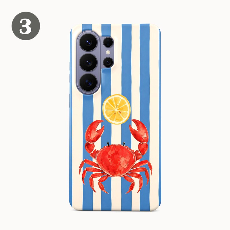 May include: A phone case with a blue and white striped background. A red crab with a yellow lemon slice above it is centered on the case. The case has a camera cutout on the top left.