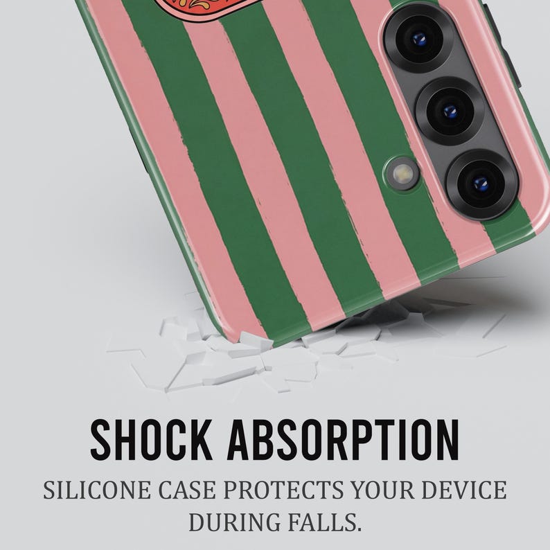May include: A smartphone case featuring a green and pink striped design. The case is angled, revealing the camera lenses and the words "SHOCK ABSORPTION". The text below reads "SILICONE CASE PROTECTS YOUR DEVICE DURING FALLS."