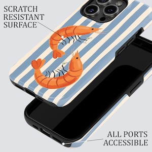 May include: A phone case with a blue and white striped design. The case features two orange shrimp illustrations, each holding a tiny cocktail glass. The text "SCRATCH RESISTANT SURFACE" and "ALL PORTS ACCESSIBLE" are also visible.
