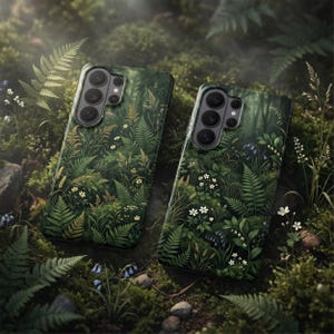 Op de afbeelding: Twee telefoonhoesjes met een bosontwerp. De hoesjes hebben een donkergroene achtergrond met gedetailleerde illustraties van varens, wilde bloemen en ander bosblad. De hoesjes hebben een cameramodule met meerdere lenzen.