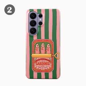 May include: A phone case with a pink and green striped design. The case features a sardine can illustration with the text "Sardines Pour Les Toasts". The sardine can is open, showing three fish.