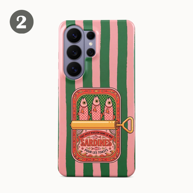May include: A phone case with a pink and green striped design. The case features a sardine can illustration with the text "Sardines Pour Les Toasts". The sardine can is open, showing three fish.