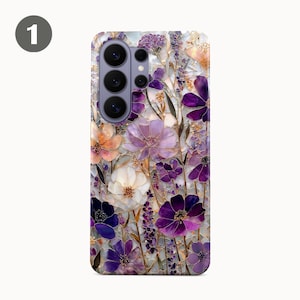 May include: A phone case featuring a floral design with purple, white, and orange flowers. The case has a glossy finish and a camera cutout. The flowers are arranged in a mosaic pattern, creating a textured appearance.