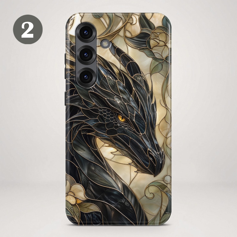 May include: A phone case featuring a black dragon with golden eyes, rendered in a stained glass style with dark outlines and cream-coloured background segments. The design includes floral motifs and a triple camera cutout on the upper left side.