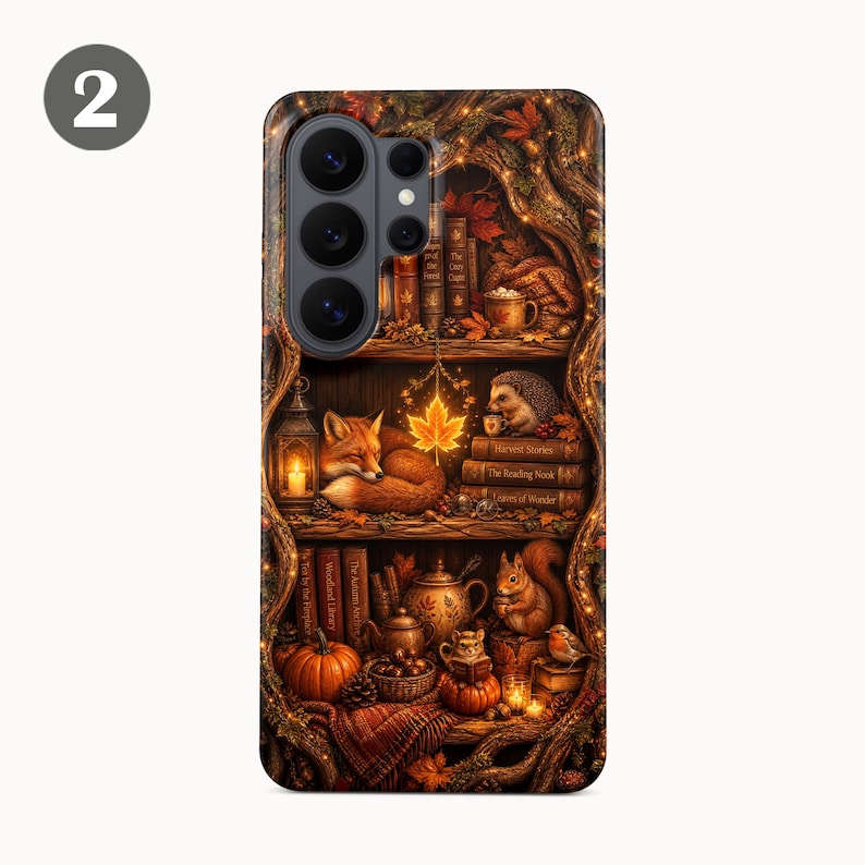 May include: A smartphone case featuring a detailed autumn-themed illustration of a hollow tree trunk filled with shelves. The design includes a sleeping fox, a hedgehog, a squirrel, books, pumpkins, lanterns, and glowing maple leaves in warm orange tones.