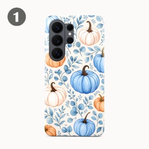 Puede incluir: Una funda para smartphone con un patr&oacute;n repetitivo de calabazas en tonos azul claro, naranja suave y crema, intercaladas con delicadas hojas azules estilo eucalipto sobre un fondo crema, con un recorte negro para la lente de la c&aacute;mara.