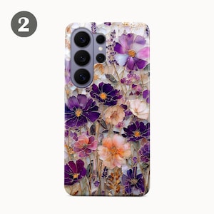 May include: A phone case featuring a floral design with purple, pink, and white flowers. The flowers have gold accents and are set against a mosaic-style background. The case has a camera cutout.