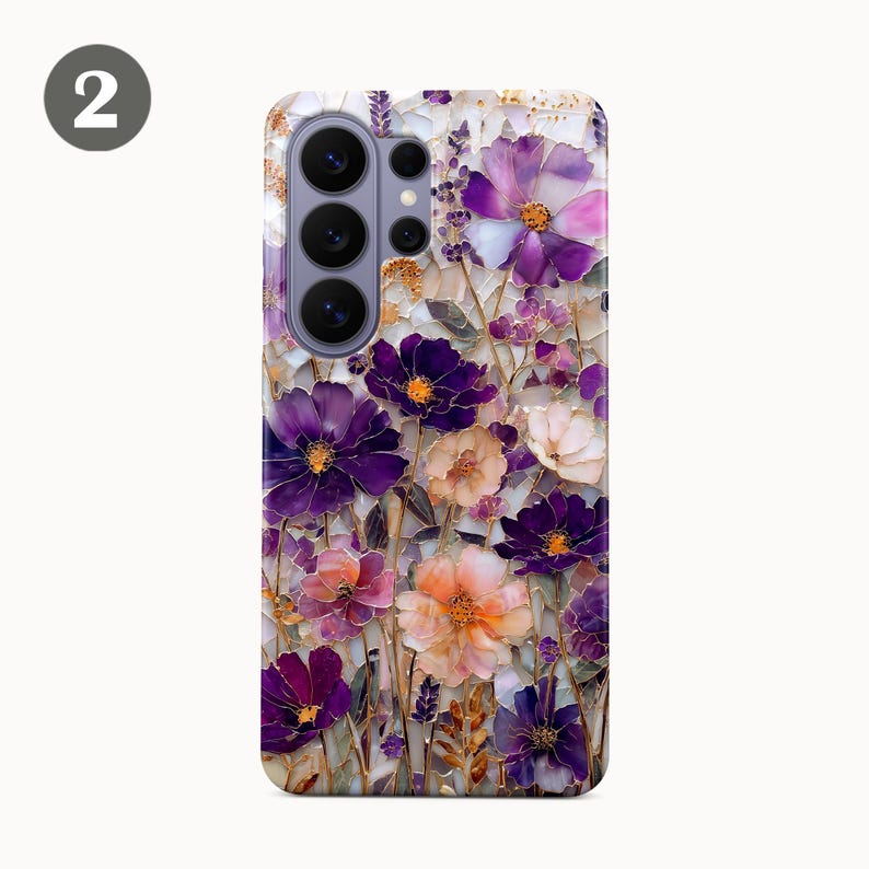 May include: A phone case featuring a floral design with purple, pink, and white flowers. The flowers have gold accents and are set against a mosaic-style background. The case has a camera cutout.