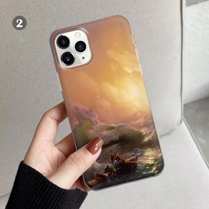 Peut inclure: Une coque de t&eacute;l&eacute;phone transparente avec une peinture color&eacute;e d'une mer orageuse avec un bateau et des personnes. La coque a un renflement de cam&eacute;ra sur&eacute;lev&eacute; avec trois objectifs d'appareil photo noirs.
