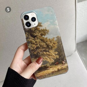 Peut inclure: Une coque de t&eacute;l&eacute;phone transparente avec un paysage peint d'une sc&egrave;ne de for&ecirc;t. La peinture repr&eacute;sente un grand arbre aux feuilles vertes, un ciel bleu avec des nuages blancs et un chemin qui traverse la for&ecirc;t. On peut &eacute;galement voir deux chevaux au loin.