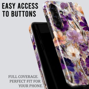 May include: A phone case with a floral design in shades of purple, white, and peach. The case has the words "EASY ACCESS TO BUTTONS" and "FULL COVERAGE. PERFECT FIT FOR YOUR PHONE." printed on it.