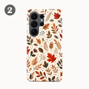 Puede incluir: Una funda rectangular para smartphone con fondo color crema y un patr&oacute;n repetitivo de hojas de oto&ntilde;o en tonos rojo, naranja y marr&oacute;n, acentuado con peque&ntilde;os puntos negros y tallos finos, con un m&oacute;dulo de c&aacute;mara negro en la parte superior.