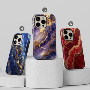 May include: Three iPhone cases with marble patterns. The case on the left is blue with gold accents, the middle case is purple with gold accents, and the case on the right is red with gold accents.