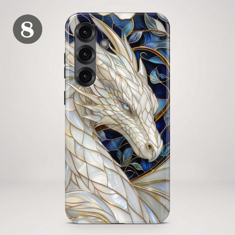 May include: A smartphone case featuring a white dragon with iridescent scales and blue eyes, set against a dark blue and gold stained glass background. The design includes intricate gold outlines and leaf motifs, with a triple camera lens cutout.