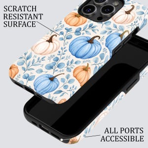 Puede incluir: Una funda para tel&eacute;fono con un patr&oacute;n de calabazas azul claro, naranja y blancas con hojas azules. La funda tiene una superficie resistente a los ara&ntilde;azos y todos los puertos son accesibles. Incluye un marco interior de color negro.