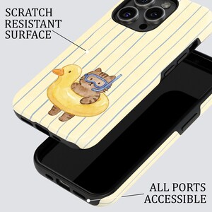 May include: A phone case with a yellow and white striped pattern. The case features a watercolor illustration of a brown tabby cat wearing goggles and floating in a yellow duck-shaped inflatable. The text "SCRATCH RESISTANT SURFACE" is visible.