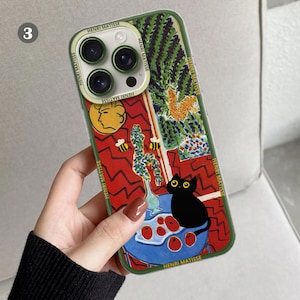 K&ouml;nnte beinhalten: Eine gr&uuml;ne Handyh&uuml;lle mit einem farbenfrohen Gem&auml;lde einer Katze, Blumen und Bienen. Das Gem&auml;lde stammt von Henri Matisse. Die H&uuml;lle hat einen Ausschnitt f&uuml;r die Kamera des Handys.
