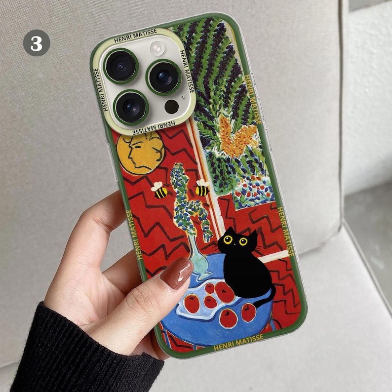 K&ouml;nnte beinhalten: Eine gr&uuml;ne Handyh&uuml;lle mit einem farbenfrohen Gem&auml;lde einer Katze, Blumen und Bienen. Das Gem&auml;lde stammt von Henri Matisse. Die H&uuml;lle hat einen Ausschnitt f&uuml;r die Kamera des Handys.