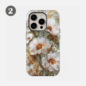 May include: A phone case featuring a floral design with large white flowers and smaller blossoms. The case has a light green and gold background, with a textured appearance. The case has a camera cutout and buttons.