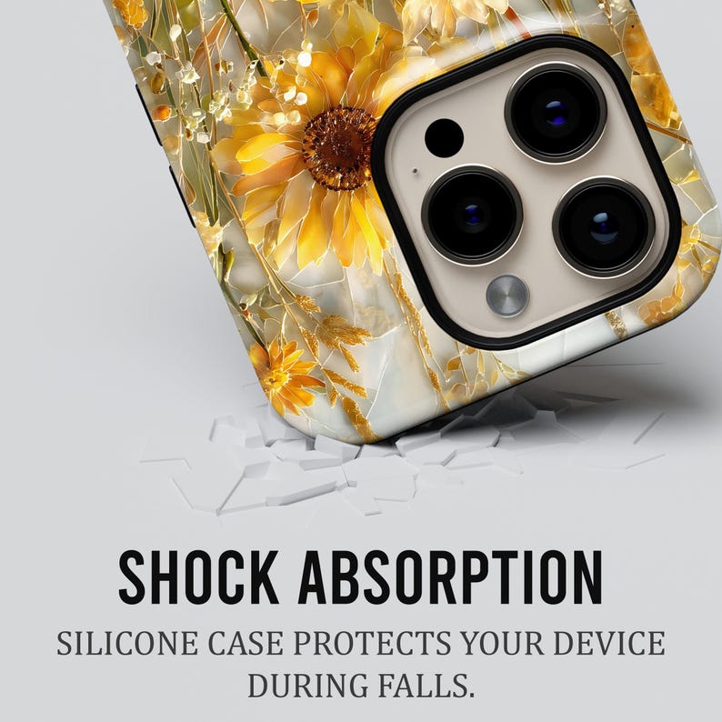 May include: A phone case with a floral design featuring sunflowers and other yellow and gold flowers. The case has a white background and a black border around the camera lenses. The text "SHOCK ABSORPTION" is visible.