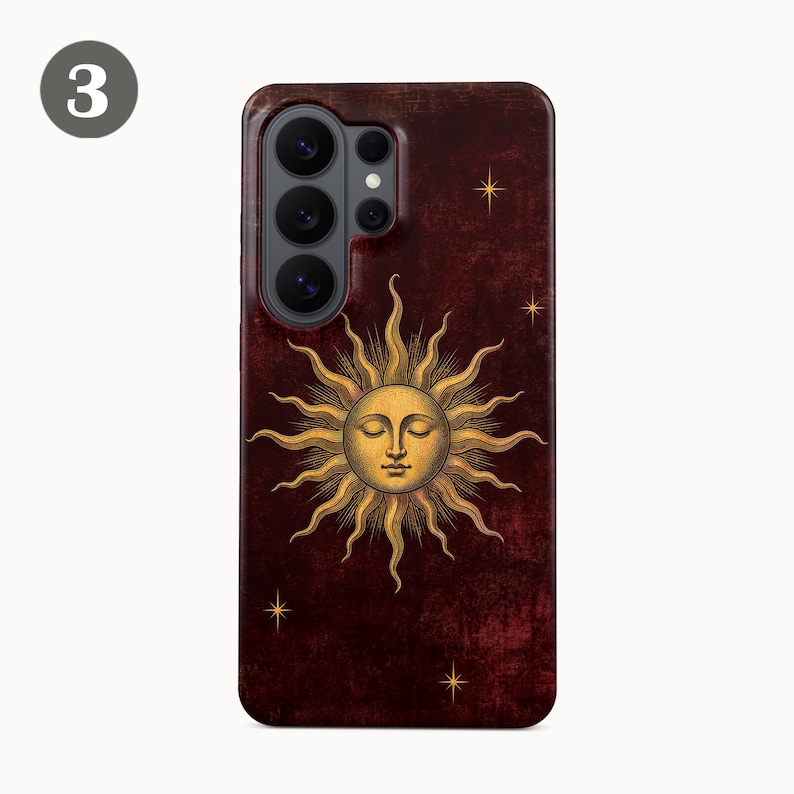 May include: A dark maroon smartphone case featuring a central gold sun illustration with a human face and closed eyes. The design includes small gold star accents scattered across the textured, deep red background, surrounding the camera lens array.
