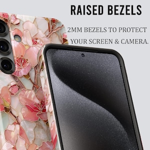 May include: A smartphone case with a floral design in shades of pink, white, and gold. The case has raised bezels for screen and camera protection. The text on the image reads "RAISED BEZELS" and "2MM BEZELS TO PROTECT YOUR SCREEN & CAMERA."