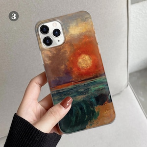 Peut inclure: Une coque de t&eacute;l&eacute;phone transparente avec une peinture d'un coucher de soleil sur l'oc&eacute;an. La peinture est dans des tons d'orange, jaune, bleu et vert. La coque a une bosse de cam&eacute;ra sur&eacute;lev&eacute;e.