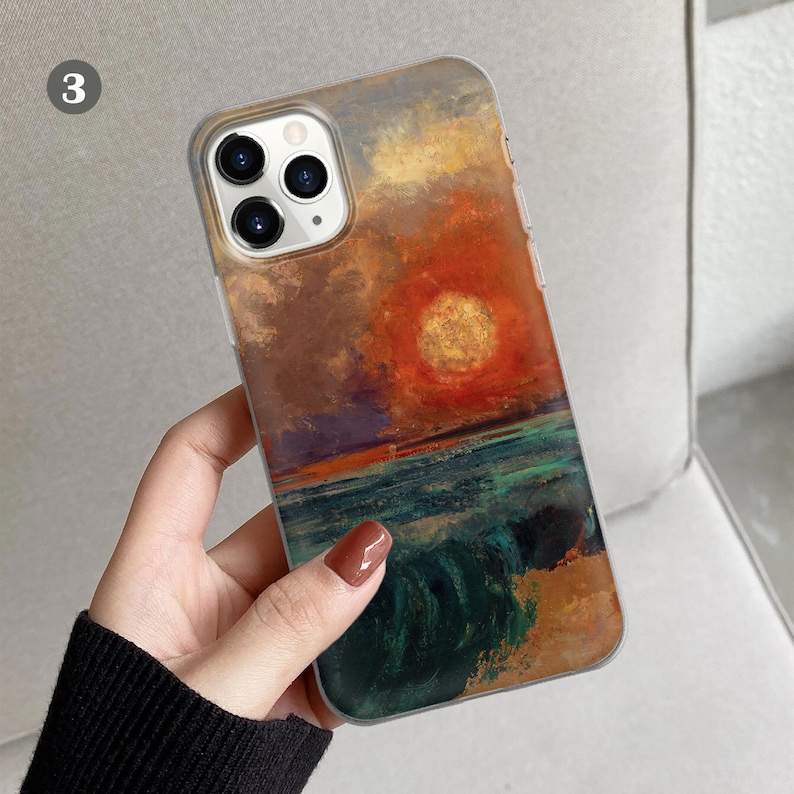 Peut inclure: Une coque de t&eacute;l&eacute;phone transparente avec une peinture d'un coucher de soleil sur l'oc&eacute;an. La peinture est dans des tons d'orange, jaune, bleu et vert. La coque a une bosse de cam&eacute;ra sur&eacute;lev&eacute;e.