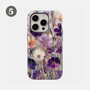 May include: A phone case featuring a floral design with purple, white, and orange flowers. The case has a glossy finish and a raised design, with a camera cutout on the top.