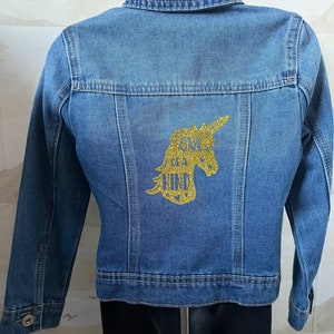 May include: A blue denim jacket with a gold glitter unicorn and the text "One of a Kind" on the back.