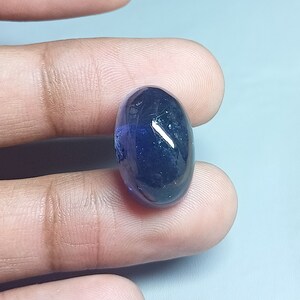 May include: A dark blue oval-shaped gemstone with a slight purple hue.