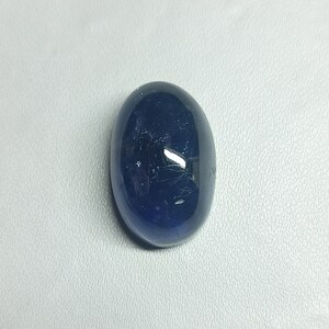 May include: A dark blue oval-shaped gemstone with a smooth, polished surface.