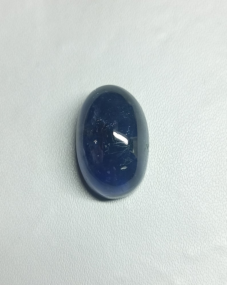 May include: A dark blue oval-shaped gemstone with a smooth, polished surface.