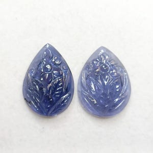 May include: Two carved amethyst pear-shaped gemstones with a floral design.