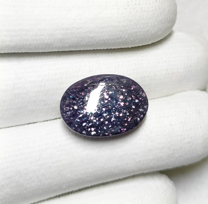 May include: A close-up of a purple and silver oval gemstone with a sparkly, iridescent finish.