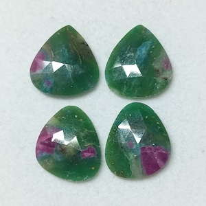 Pode incluir: Quatro cabochões de pedras preciosas verdes, rosas e azuis com um corte facetado. As pedras têm a forma de pêra e têm uma aparência translúcida.