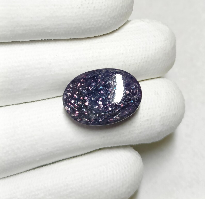 May include: A close-up of a purple and white oval gemstone with a sparkly, iridescent finish.