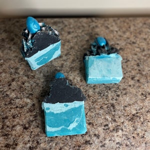 May include: Three handmade soap bars with a black and blue swirl design. The soap bars have a decorative swirl on top.
